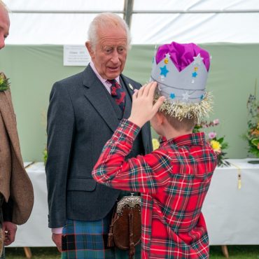 Schoolboy tries on prize winning cardboard crown in front of the King